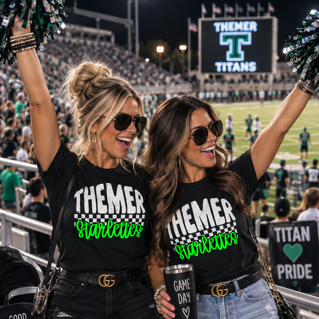 Two women cheering at a football game wearing matching black 'THEMER Harlequin' graphic t-shirts and holding green pom-poms. The background shows a stadium with a large 'THEMER TITANS' scoreboard.