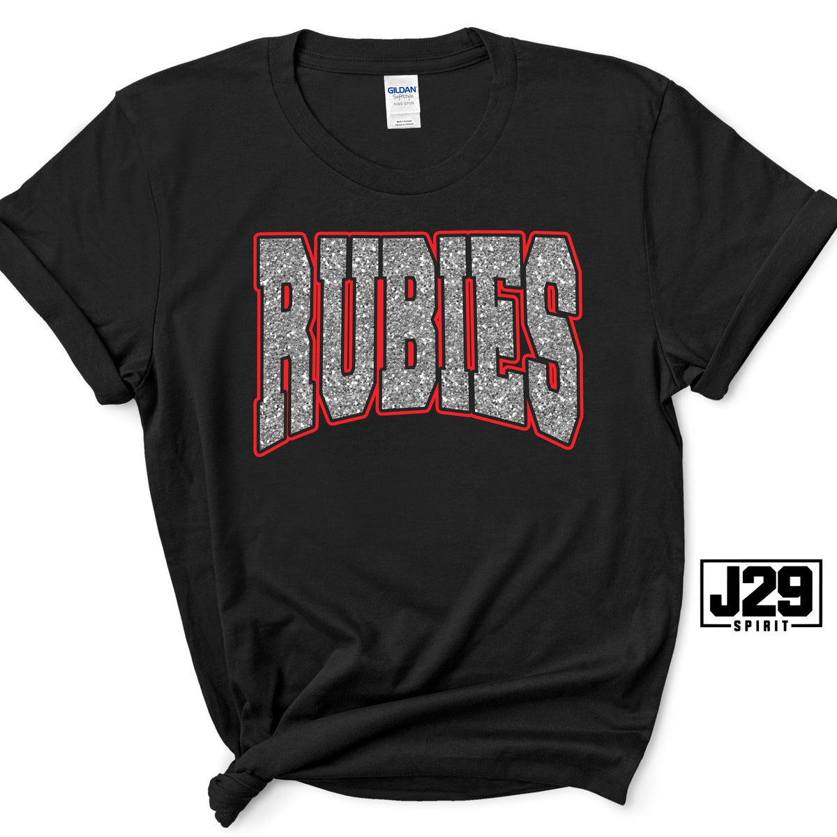 A black short-sleeve t-shirt with a graphic reading 'RUBIES' in silver glitter-style letters with a red outline, displayed on a white background with a J29 Spirit logo overlay.