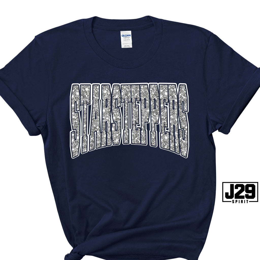 A navy blue short-sleeve t-shirt with a large arched 'STAMPEERS' graphic across the chest filled with a gray and white camouflage pattern and outlined in white. The shirt is displayed flat against a white background with a small 'J29 SPIRIT' logo overlay in the bottom right corner.